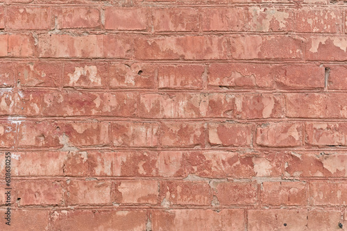 a shabby old wall with peeling red brick paint