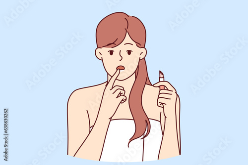 Woman with lipstick in hand, embarrassment looks at screen instead of mirror and needs healing lip balm. Girl in bath towel uses hygienic lipstick after shower and recommends using cosmetics