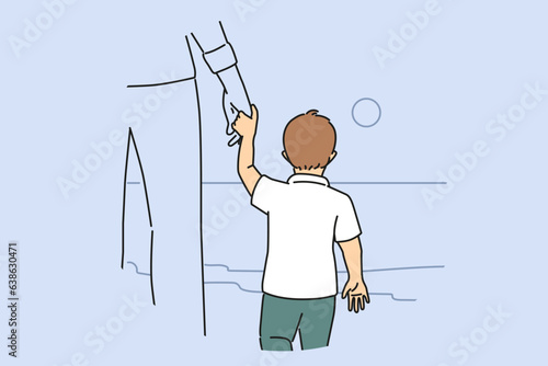 Little boy holds father hand and look at sea, enjoy walk together during sunset, view from back. Father and son are standing on beach near sea or ocean, dreaming of going on trip to distant island.