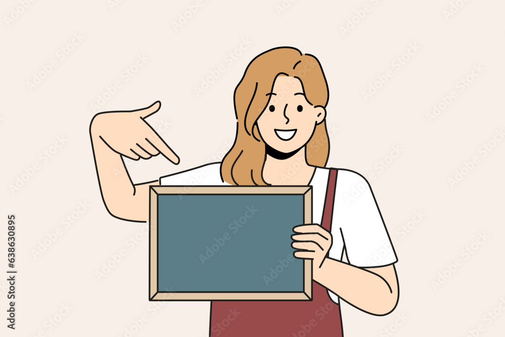 Woman waiter is holding chalkboard with copy space for drawing menu or promotional offers from restaurant. Cheerful girl waiter in apron points with finger at place for name of bar or cafe logo Woman waiter is holding chalkboard with copy space for drawing menu or promotional offers from restaurant. Cheerful girl waiter in apron points with finger at place for name of bar or cafe logo