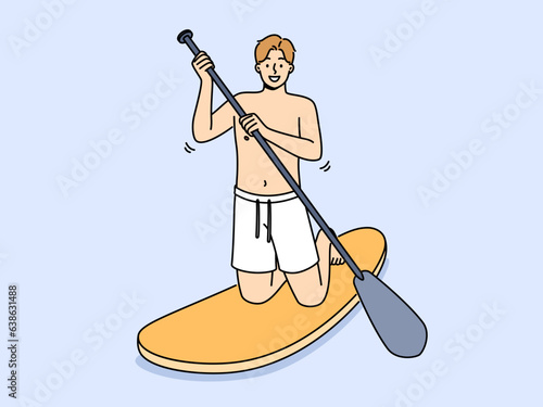 Man rides sup board with oar in hands and smiling looks at screen, encouraging exercise water sports. Guy swims on sup board enjoying active lifestyle, and possibility of visiting sea or ocean