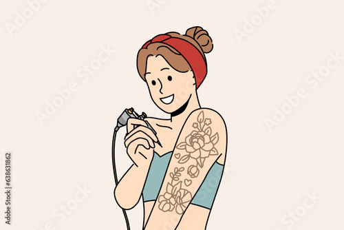 Woman tattoos hand on own and smiles, offering to use services of professional tattoo artist. Young girl working in tattoo parlor holds equipment for drawing picture under skin with needle.