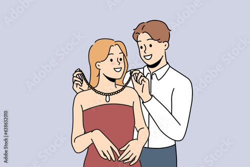 Loving man puts necklace around girlfriend neck to help get ready for party. Rich boyfriend courts girl and gives precious necklace as sign of seriousness of romantic relationship.