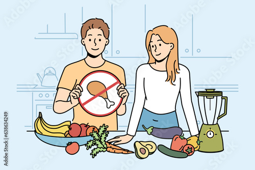 Cooking vegan show with man and woman standing in kitchen with vegetables and demonstrating crossed out meat sign. Guy and girl are preparing vegetarian dish, recommend diet of healthy food