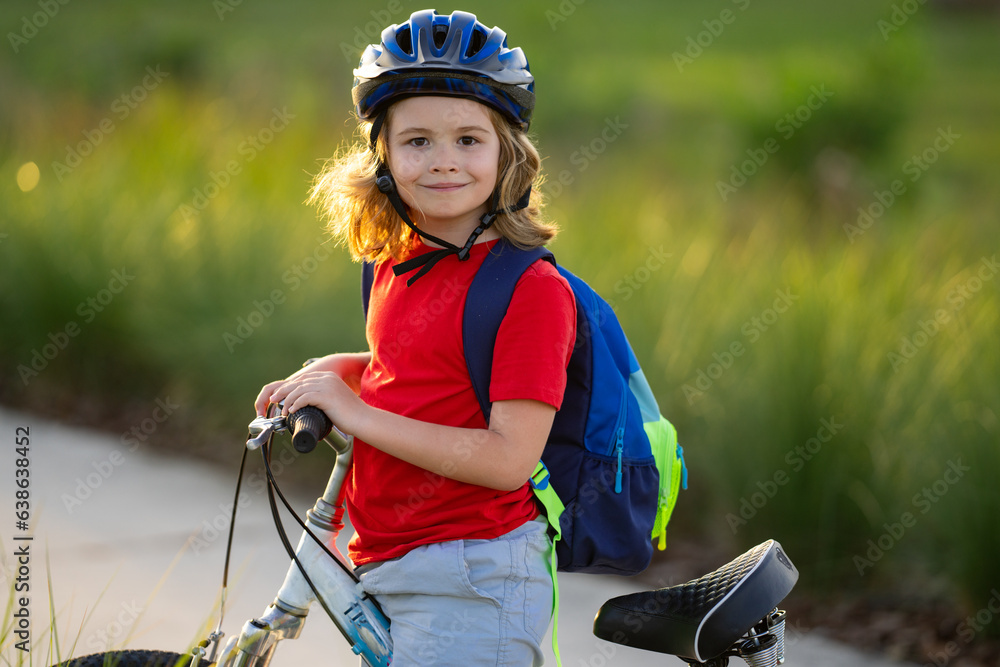 Obraz premium Child on bicycle. Boy in a helmet riding bike. Little cute caucasian boy in safety helmet riding bike in city park. Child first bike. Kid outdoors summer activities. Kid on bicycle. Boy ride a bike.