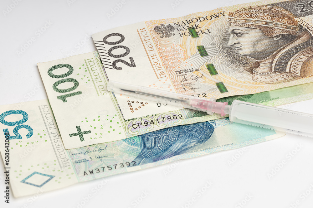 Polish banknotes of PLN lying on a white background, next to a syringe with a needle (selective focus) Polish banknotes of PLN lying on a white background, next to a syringe with a needle (selective focus)