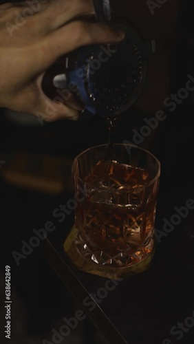 Bartender pouring cocktail Negroni into glass