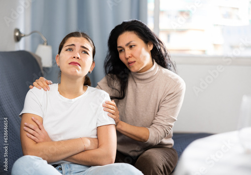 Asian woman comforting her depressed friend, European woman, at home.