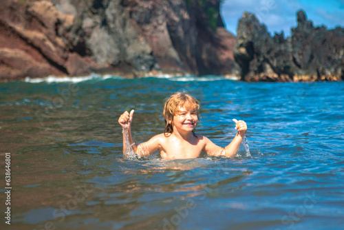 Happy kid have fun on tropical sea beach resort. Funny boy with splashes by water. Active kids lifestyle, swimming activity on summer holiday with children.