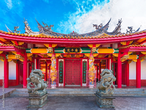 nagasaki, kyushu - dec 13 2022: Red gate of the Japanese Confucius Shrine called Kōshi-byō adorned with golden dragons and fenghuang phoenix on it and protected by two chinese shishiko guardian lions. photo