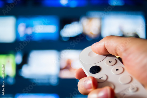 Detail shot of man's hand holding remote control of smart TV