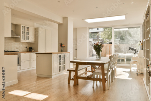 a kitchen and dining area in a house with white cabinets, wood flooring and an open door leading to the patio