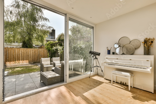 a living room with a piano in the center and an open patio door leading to the back yard on the right side