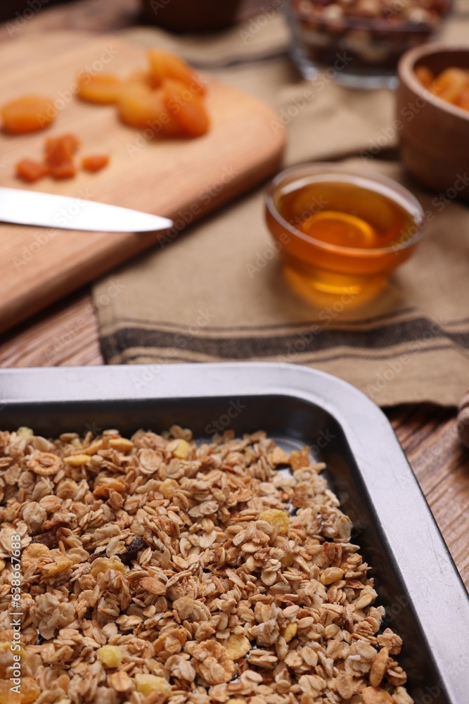 Making granola. Baking tray with mixture of oat flakes and other ingredients on wooden table, closeup Making granola. Baking tray with mixture of oat flakes and other ingredients on wooden table, closeup