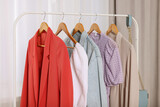 Clothing rack with stylish women's clothes on wooden hangers indoors
