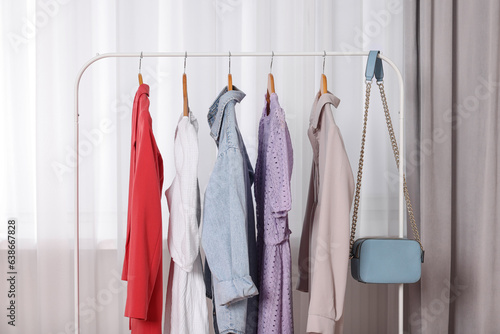 Clothing rack with stylish women's clothes on wooden hangers indoors © New Africa