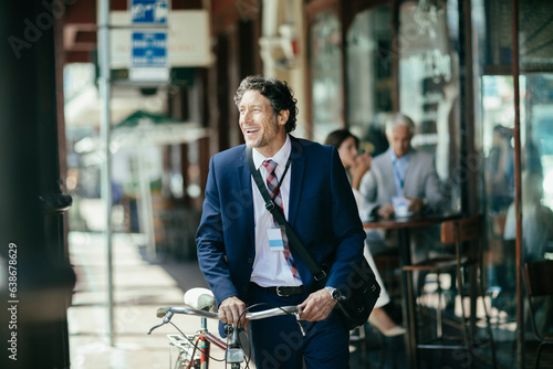 Young caucasian businessman commuting to work and pushing his bicycle in the city photo