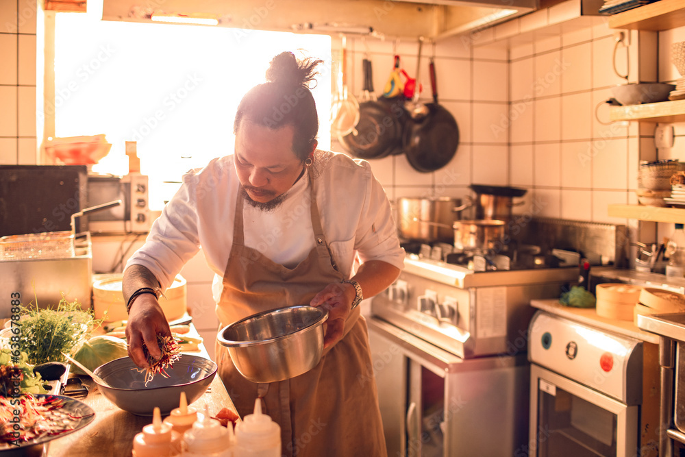 © Marko Geber - Male asian chef preparing a traditional food dish in a restaurant kitchen