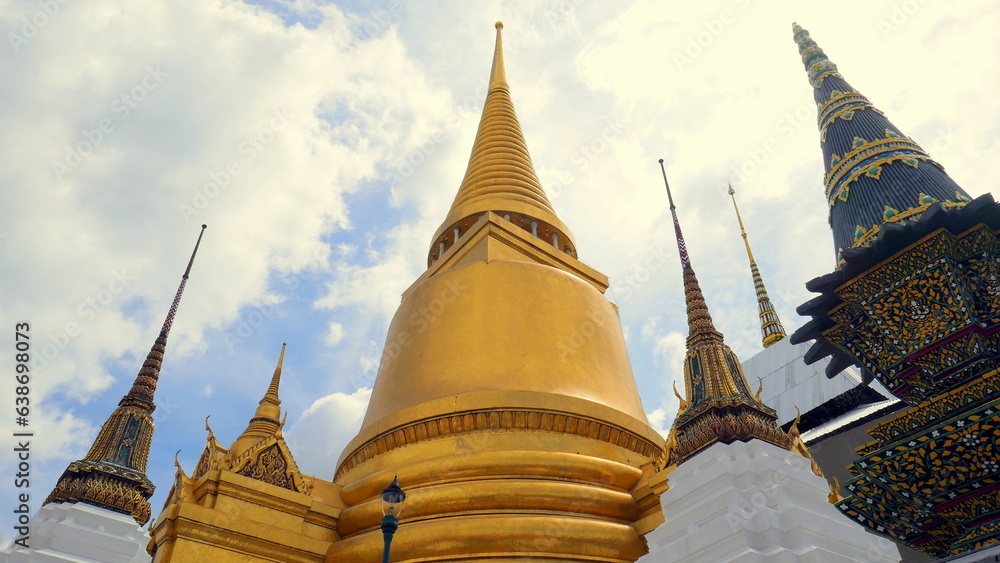 Fototapeta premium herrlicher Tempel Wat Phra Kaeo in Bangkok mit Stupas, goldener Pagode unter blauem Himmel mit Wolken