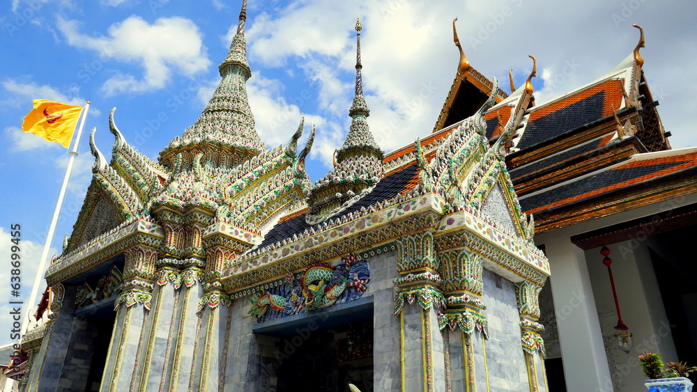 Herrlicher Tempel Wat Phra Kaeo mit Stupas und Säulen und rotem Dach unter blauem Himmel Herrlicher Tempel Wat Phra Kaeo mit Stupas und Säulen und rotem Dach unter blauem Himmel