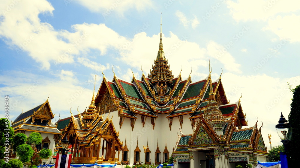 Naklejka premium Herrlicher Tempel Wat Phra Kaeo mit vergoldeten Stupas und rotem Dach unter blauem Himmel