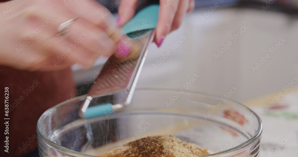 Grating fresh whole nutmeg over a mixing bowl closup Grating fresh whole nutmeg over a mixing bowl closup
