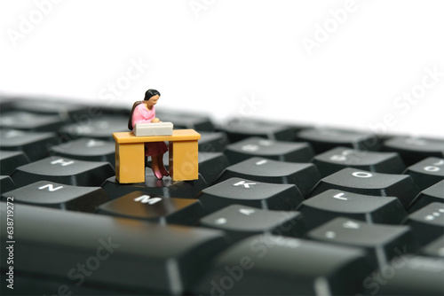 Miniature tiny people toy figure photography. A woman seat in the desk, working above keyboard. Isolated on a white background