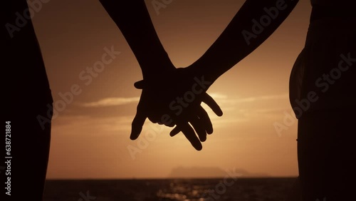 Close up silhouette man and woman touching hands together at sunset beach. Romantic couple couple holding each other hand's enjoying romantic date. Love couple holding hands on sea sunset background.
