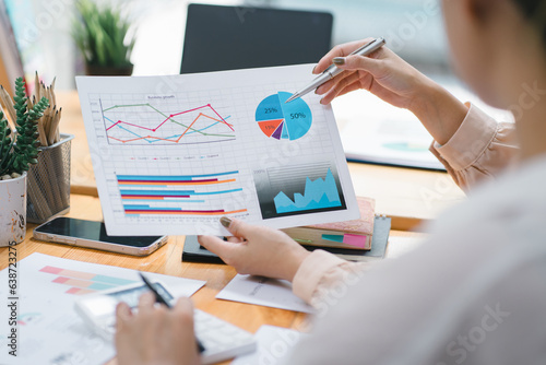 Two businesspeople or an accountant team are analyzing data charts, graphs, and a dashboard on a laptop screen in order to prepare a statistical report and discuss financial data in an office.