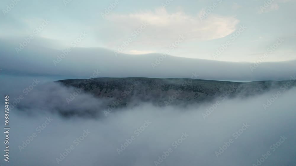 Aerial orbit shot above the white clouds with a view of a steep rocky mountain ridge emerging from the cloud cover in Sweden Aerial orbit shot above the white clouds with a view of a steep rocky mountain ridge emerging from the cloud cover in Sweden