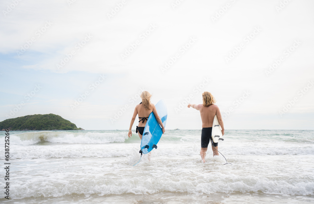 Young man and woman holding surfboards ready to walk into the sea to surf. Young man and woman holding surfboards ready to walk into the sea to surf.