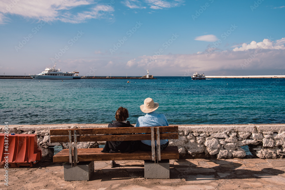 pareja de personas mayores sentadas en un banco mirando al mar