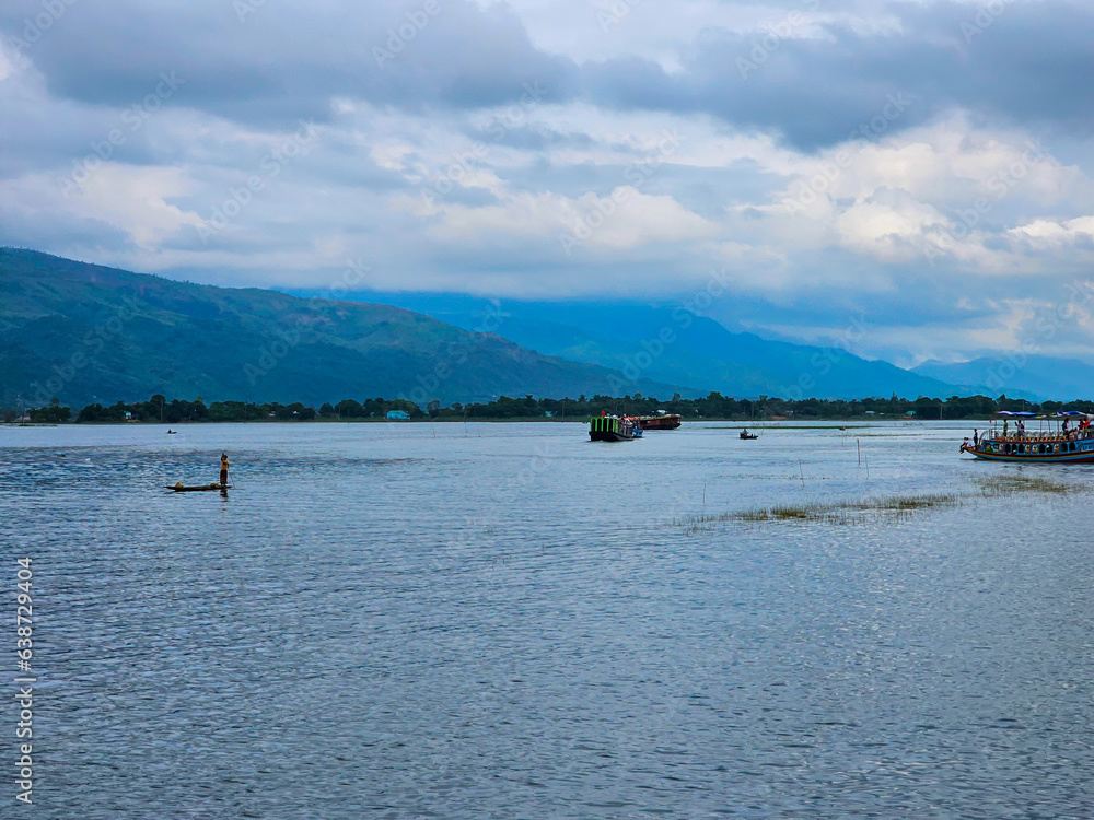 Tanguar Haor Houseboat sailing on the river near the India border in Bangladesh during the rainy season with the beautiful Meghalayan hills at the background.