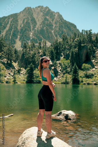 Girl in a lake next to a mountain looking at camera