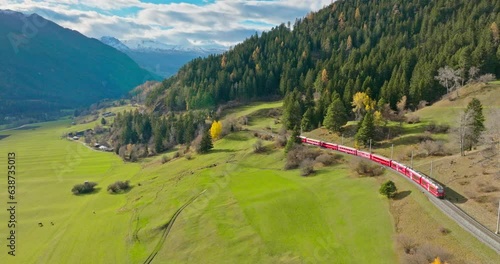 Aerial view of a world heritage sightseeing luxury Glacier and Bernina express in Swiss Alps autumn summer scenery. Drone shot red train goes through the famous mountain in Filisur, Switzerland.
