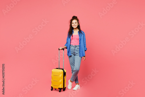 Traveler smiling woman wears blue shirt casual clothes hold suitcase isolated on plain pink background studio. Tourist travel abroad in free spare time rest getaway. Air flight trip journey concept.