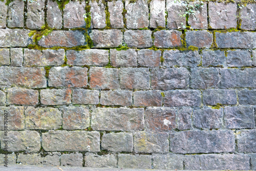 Fototapeta premium Granite stonewall with green grass background texture.