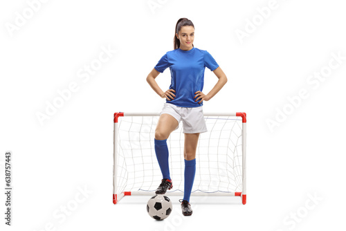 Full length portrait of a female football player posing in front of a mini goal