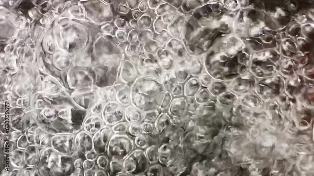 slow-motion closeup shot of air bubbles on the water surface of a little stream from above, bubbles moving an rearranging slow-motion closeup shot of air bubbles on the water surface of a little stream from above, bubbles moving an rearranging