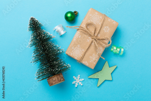 Miniature christmas tree with gift box and decor on color background