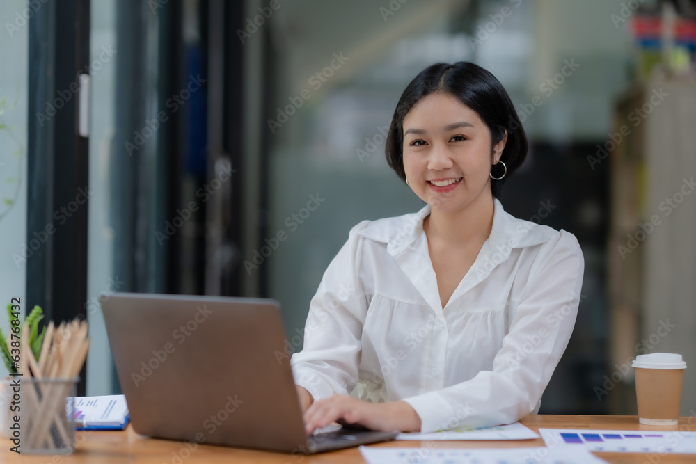 Successful Asian businesswoman smiling using laptop computer at office. Confident Asia businesswoman sitting happily in the office. Successful Asian businesswoman smiling using laptop computer at office. Confident Asia businesswoman sitting happily in the office.