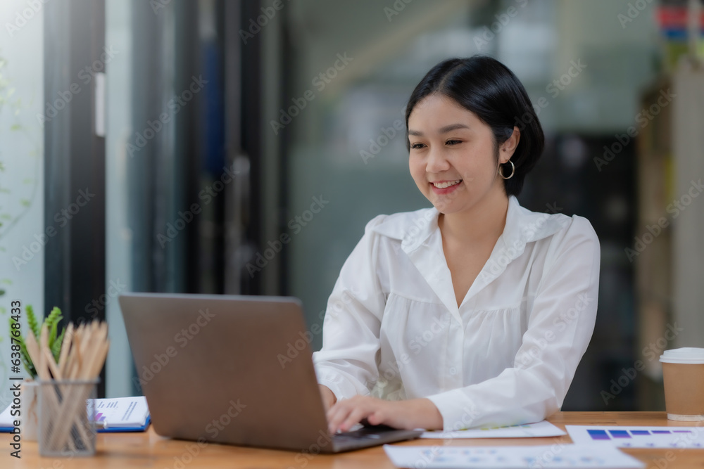 Successful Asian businesswoman smiling using laptop computer at office. Confident Asia businesswoman sitting happily in the office. Successful Asian businesswoman smiling using laptop computer at office. Confident Asia businesswoman sitting happily in the office.