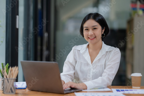 Successful Asian businesswoman smiling using laptop computer at office. Confident Asia businesswoman sitting happily in the office.