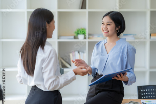 Two Asian businesswomen are consulting on marketing planning, a new corporate sales strategy in line with current events.