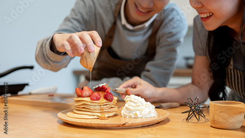 Close-up image of a handsome young Asian man enjoys cooking pancakes with his girlfriend