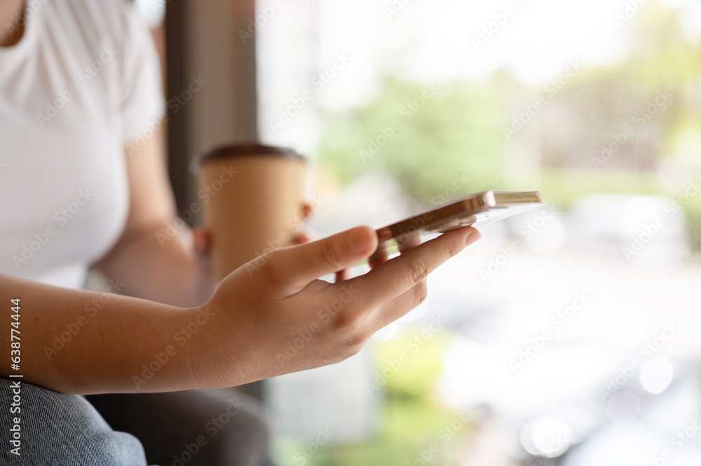 Close-up image of a female using her smartphone while sitting in a coffee shop. message, SMS