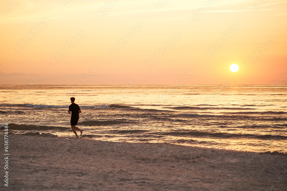 Silhouette of a Sportsman Running at Ocean Sunset. One person running against the sun.