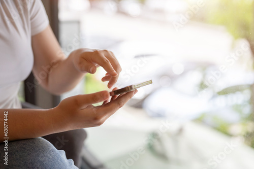 Close-up image of a female using her smartphone while sitting in a coffee shop.