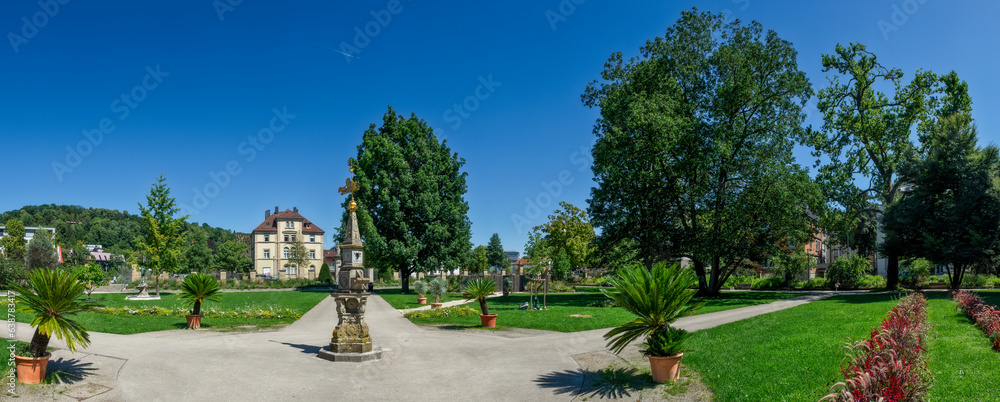 Obraz premium Panoramafoto im Stadtgarten von Schwäbisch Gmünd mit Beeten, Weg, Sonnenuhr und stahlblauem, wolkenlosem Himmel bei Sommerwetter