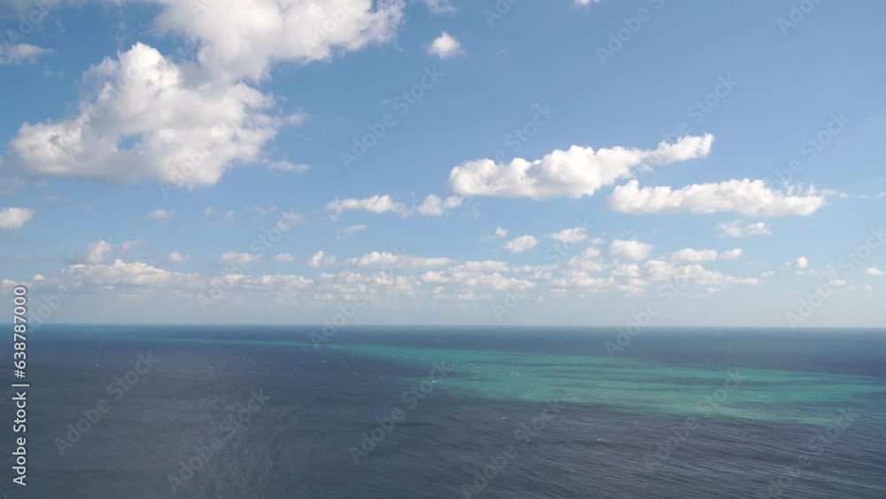 Aerial view on azure sea with fluffy Cumulus clouds moving in bright sunset sky over calm sea. Nature summer ocean sea beach background. Nobody. Weather and Climate Change. Holiday and travel concept Aerial view on azure sea with fluffy Cumulus clouds moving in bright sunset sky over calm sea. Nature summer ocean sea beach background. Nobody. Weather and Climate Change. Holiday and travel concept